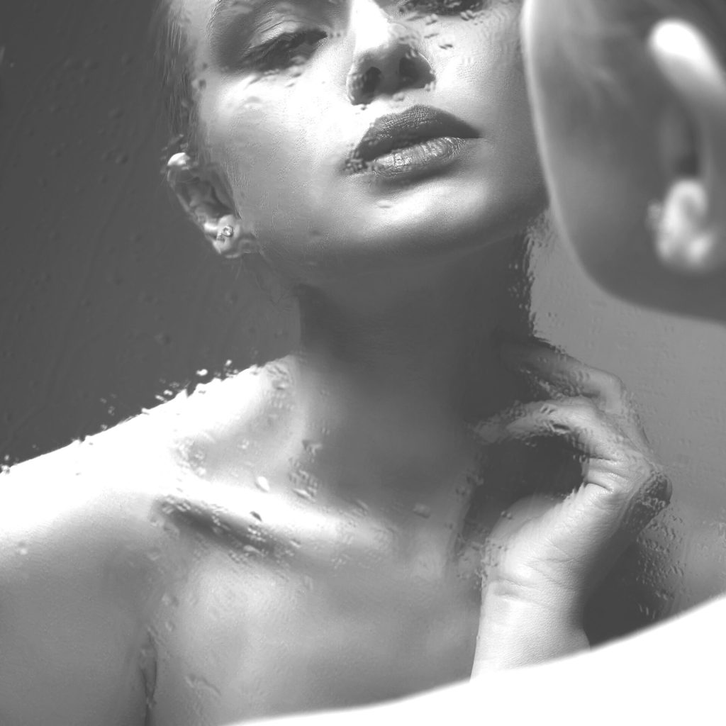 Reflection of Beautiful Girl in wet mirror. Black and white portrait of beauty Young woman in mirror